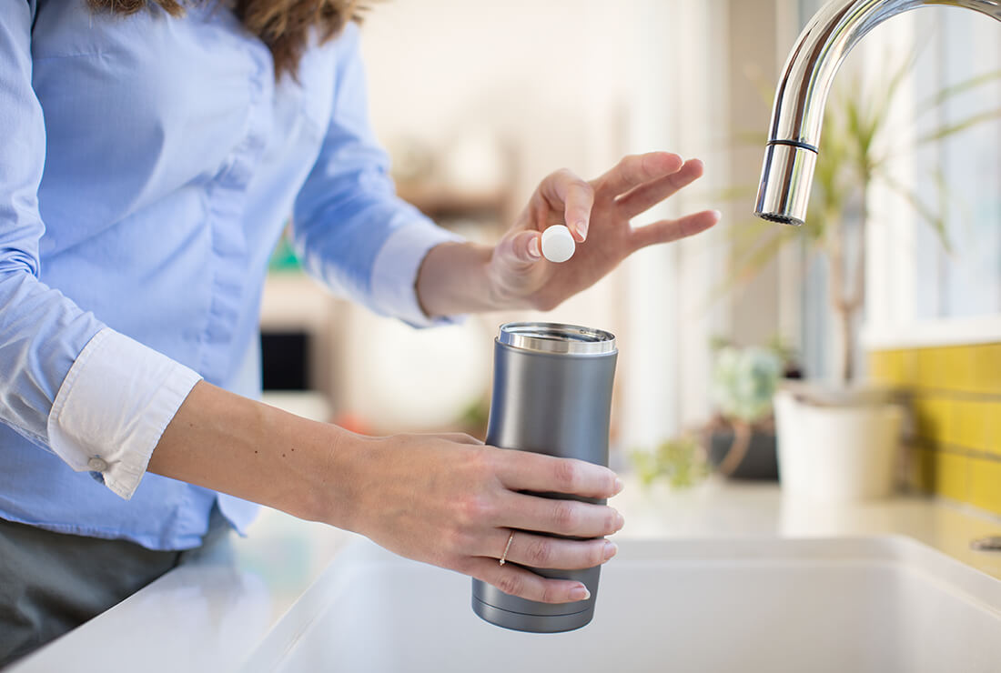 a woman using bottle bright at the kitchen sink